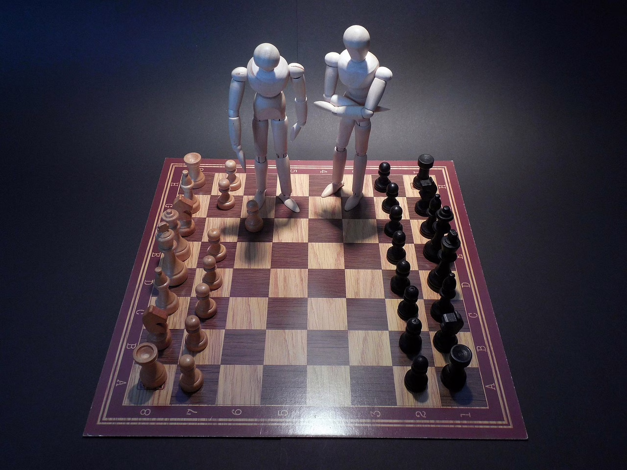 Auf einem Schachbrett stehen zusätzlich zwei größere Figuren, die überlegen.